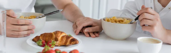 Cropped view of young couple holding hands near delicious breakfast on table, banner — Foto stock