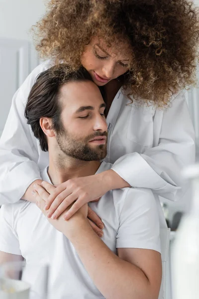 Sensual young woman hugging bearded boyfriend in kitchen — Stock Photo