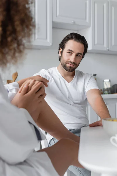 Curly young woman seducing bearded boyfriend in kitchen — Stock Photo