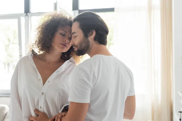 Bearded man in t-shirt seducing sensual girlfriend in white shirt — Photo de stock