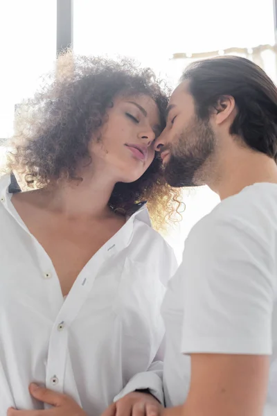 Low angle view of bearded man with closed eyes near sensual girlfriend in white shirt — Photo de stock