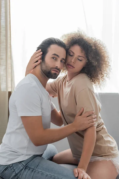 Young woman in beige t-shirt hugging bearded boyfriend in bedroom - foto de stock