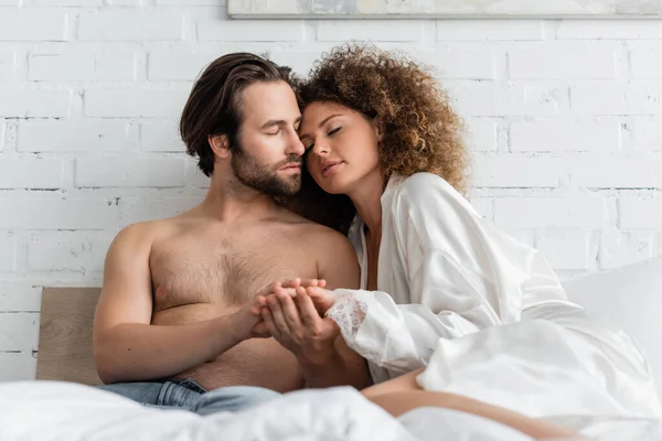 Young and sexy couple with closed eyes holding hands while resting in bed — Stockfoto