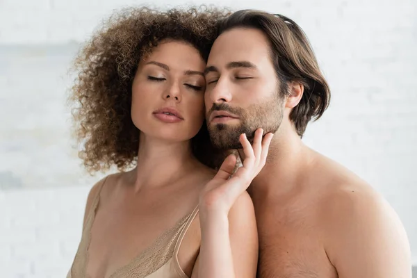 Sexy woman in silk night dress touching face of bearded and shirtless man — Foto stock