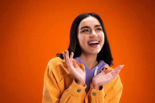 Cheerful brunette woman looking away isolated on orange — Stockfoto