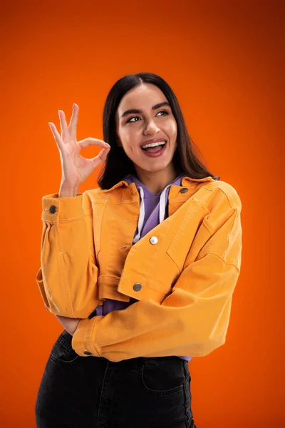 Positive young woman showing ok gesture isolated on orange — Stockfoto