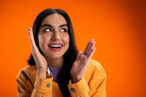 Positive young woman looking away isolated on orange — Stockfoto