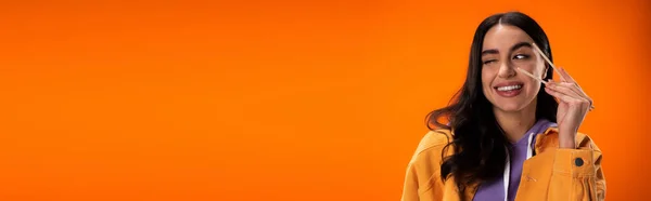 Young woman holding bamboo chopsticks and winking isolated on orange, banner — Fotografia de Stock