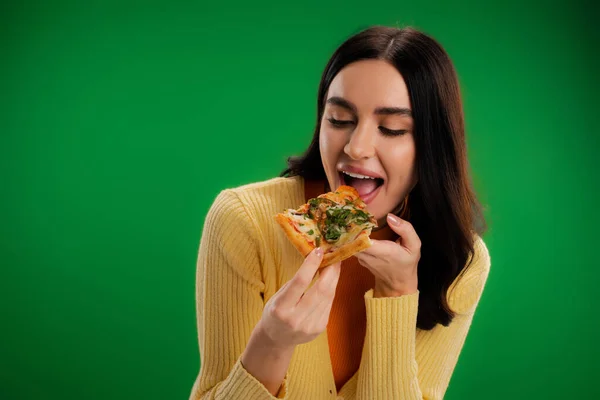 Pretty brunette woman eating tasty pizza isolated on green — Stock Photo