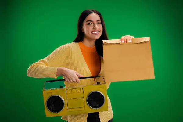 Happy woman holding boombox and food package isolated on green — Foto stock