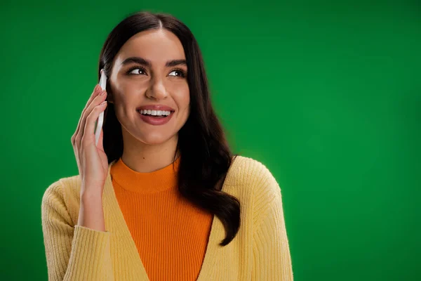 Young and happy woman in stylish clothes talking on mobile phone isolated on green — Stock Photo
