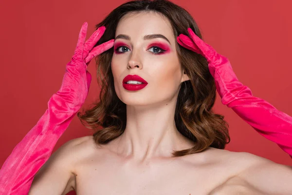 Portrait of young woman with magenta color eye shadow posing in trendy gloves isolated on pink - foto de stock