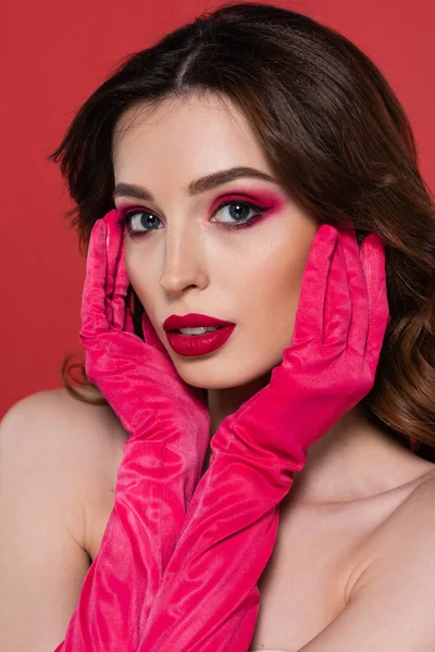 Portrait of young woman with magenta color eye shadow looking at camera isolated on pink — Stockfoto