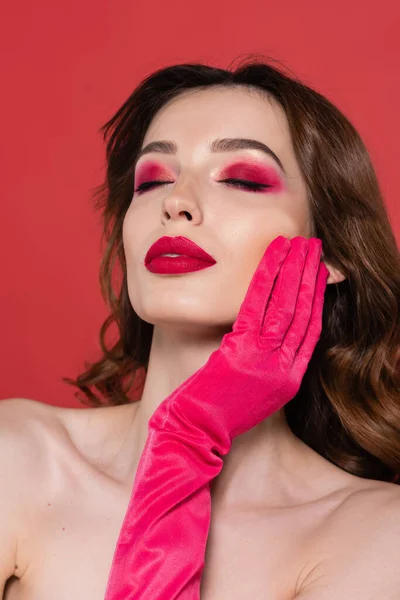 Портрет молодої жінки з закритими очима в кольоровій рукавичці пурпурового кольору, торкаючись обличчя ізольовано на рожевому — стокове фото