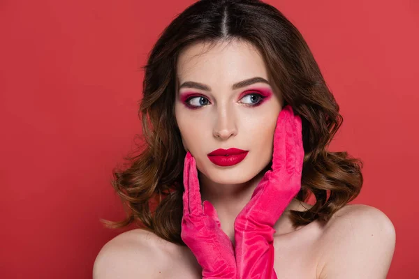Portrait of young woman with magenta color eye shadow and gloves posing isolated on pink — Stock Photo