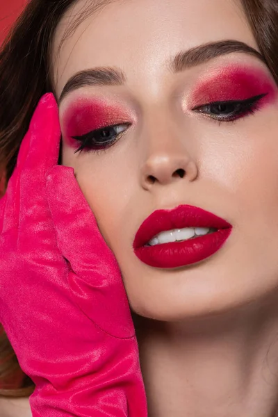 Close up of young woman with magenta color glove touching face — Fotografia de Stock