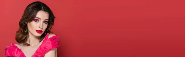 Jeune femme avec ombre à paupières de couleur magenta debout avec les bras croisés tout en s'embrassant isolée sur rose, bannière — Photo de stock