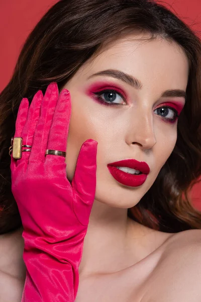 Portrait of young woman with magenta color makeup and glove with golden rings isolated on pink - foto de stock
