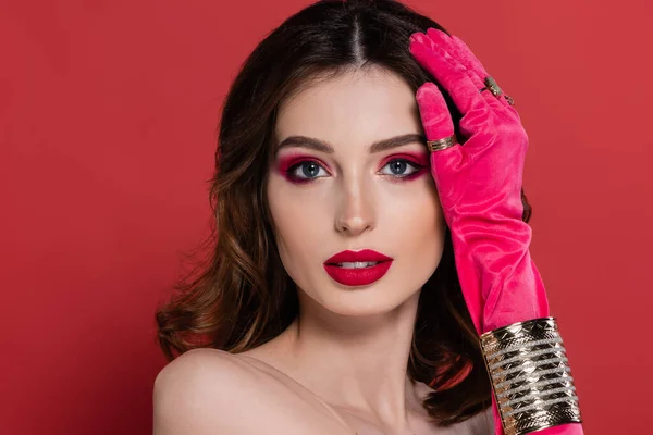Portrait of young woman in magenta color glove with golden rings and bracelet posing isolated on pink — Stockfoto
