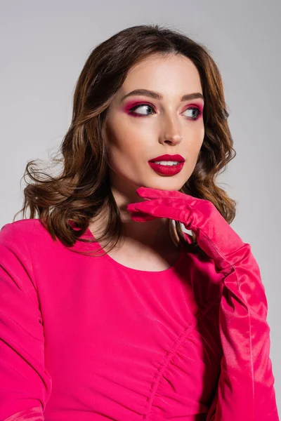 Pretty young woman with magenta color glove and dress looking away isolated on grey — Stockfoto