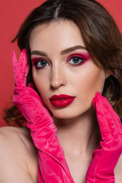 Portrait of young woman with magenta color makeup and bright gloves looking at camera isolated on pink — Foto stock