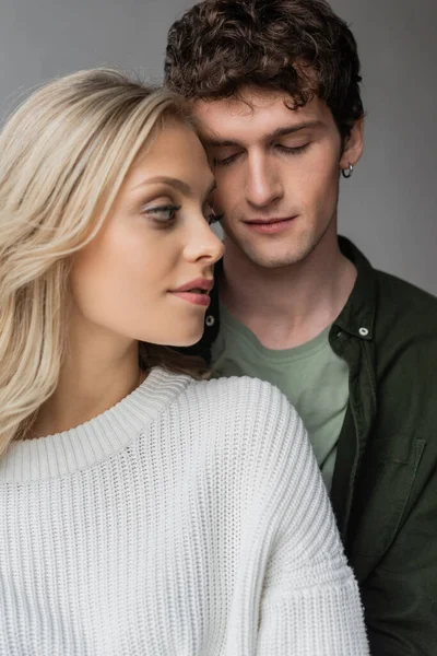 Portrait of curly young man with closed eyes near blonde woman in white sweater - foto de stock