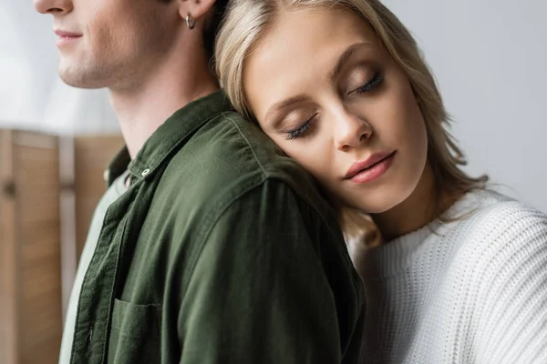 Portrait of young blonde woman with closed eyes leaning on back of man — Stock Photo