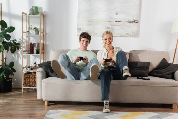 KYIV, UKRAINE - OCTOBER 24, 2022: excited young couple holding joysticks while playing video game — Photo de stock