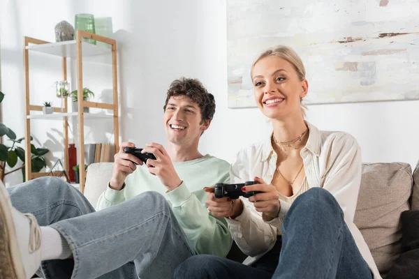 KYIV, UKRAINE - OCTOBER 24, 2022: joyful young couple holding joysticks while playing video game — Photo de stock