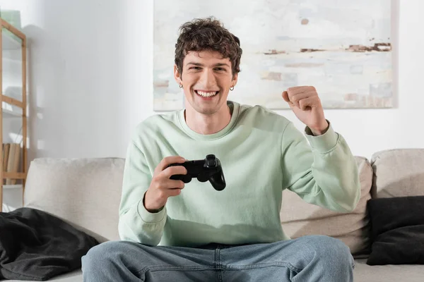KYIV, UKRAINE - OCTOBER 24, 2022: excited young man in sweatshirt playing video game — Stock Photo