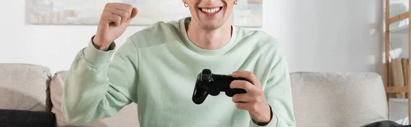 KYIV, UKRAINE - OCTOBER 24, 2022: cropped view of excited young man in sweatshirt playing video game, banner — стокове фото