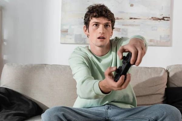 KYIV, UKRAINE - OCTOBER 24, 2022: focused young man in sweatshirt playing video game — Stock Photo