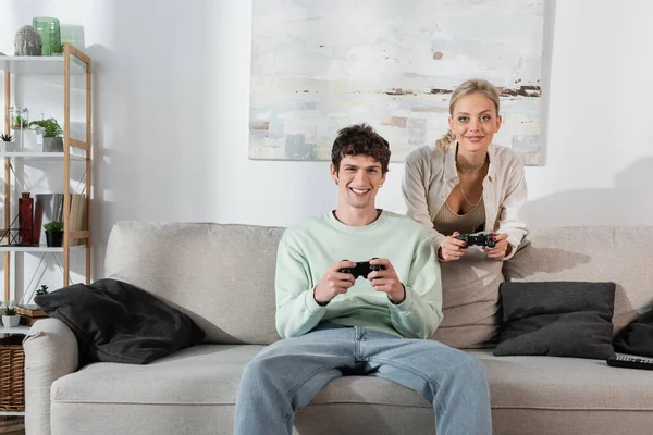 KYIV, UKRAINE - OCTOBER 24, 2022: smiling young couple playing video game at home — стокове фото