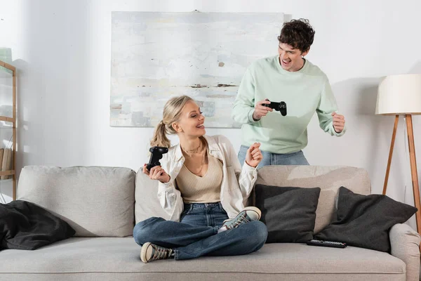KYIV, UKRAINE - OCTOBER 24, 2022: joyful young couple holding joysticks while playing video game at home — Stock Photo