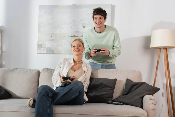 KYIV, UKRAINE - OCTOBER 24, 2022: joyful young couple holding joysticks while playing video game in living room — Stock Photo