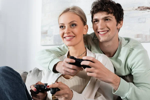 KYIV, UKRAINE - OCTOBER 24, 2022: joyful young couple holding joysticks while playing video game — стокове фото