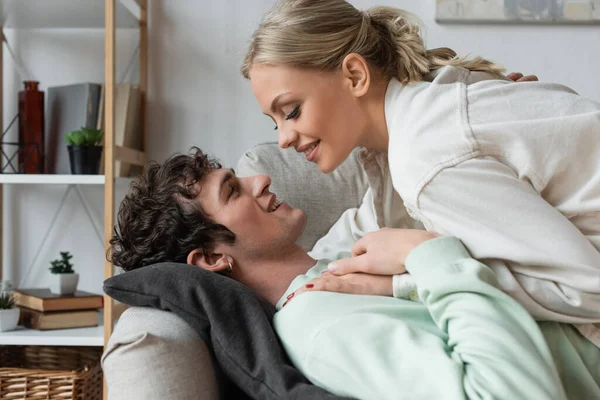 Side view of happy young couple lying on couch in living room — Photo de stock