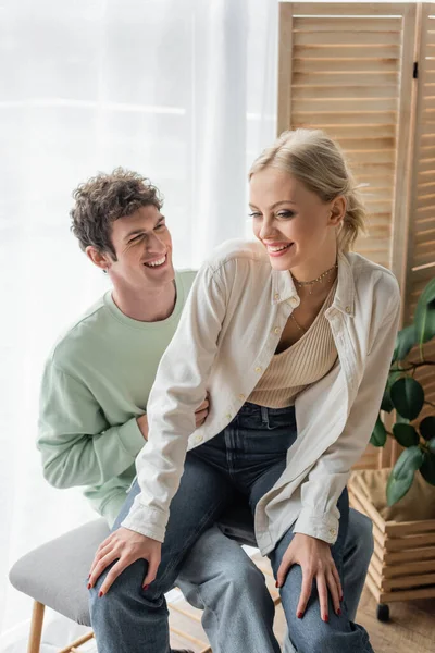 Pleased young woman sitting with happy boyfriend on bed bench — Stock Photo