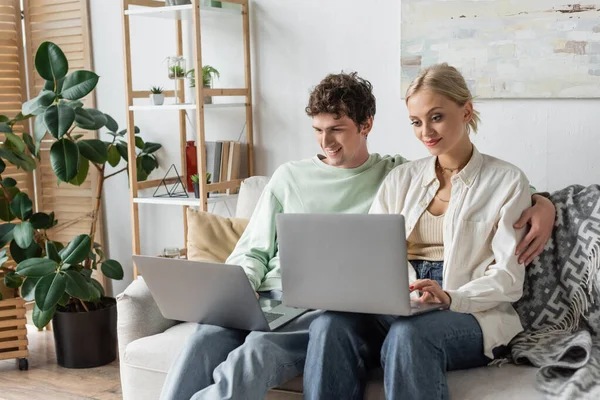 Cheerful man and woman using laptops while working from home in living room — Stock Photo