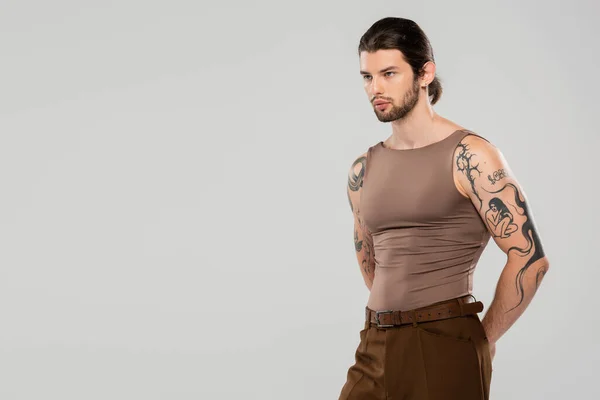 Long haired tattooed man looking away while standing isolated on grey — Stock Photo