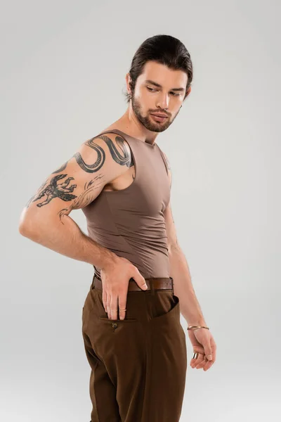 Brunette bearded man with tattoo posing isolated on grey - foto de stock