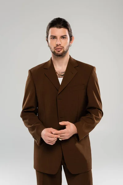 Stylish young man in brown jacket looking at camera isolated on grey - foto de stock