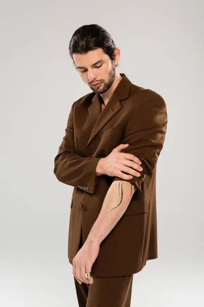 Bearded and tattooed man posing in jacket isolated on grey — Stockfoto