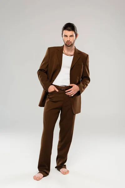 Full length of barefoot man in stylish suit posing on grey background — Stock Photo