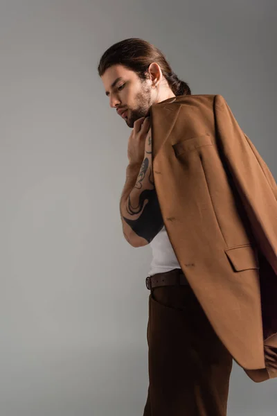 Stylish long haired model posing with jacket isolated on grey — Stock Photo