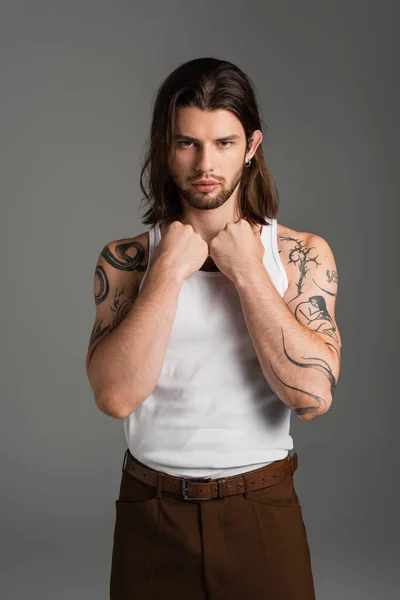 Stylish long haired model with tattoo on body looking at camera isolated on grey — Stockfoto