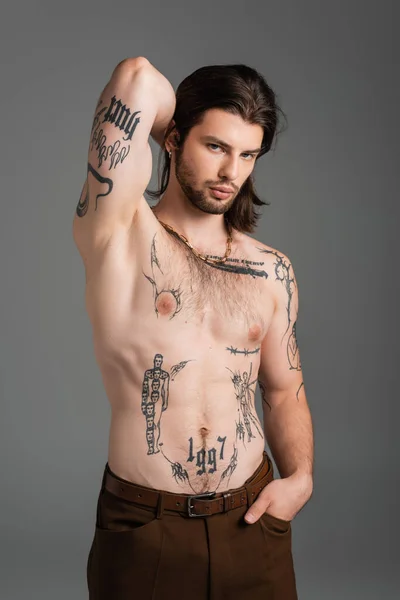 Muscular and tattooed man in pants posing isolated on grey — Photo de stock