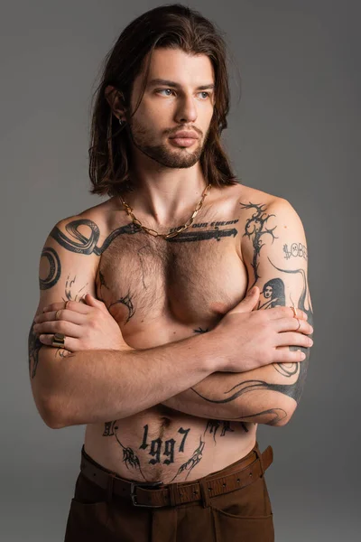 Muscular and tattooed model crossing arms isolated on grey — Photo de stock