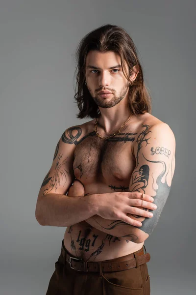 Muscular tattooed model posing while standing isolated on grey — Photo de stock