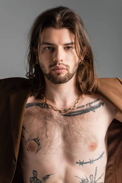 Tattooed and long haired man in jacket standing isolated on grey — Stock Photo